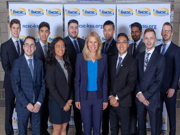 11 students stand in front of a national collegiate sales competition banner