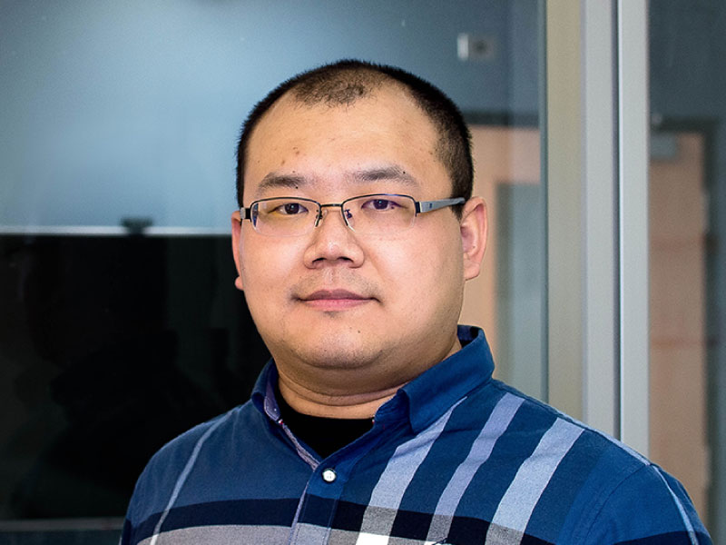 Sibo Chen wearing a blue shirt looking into the camera