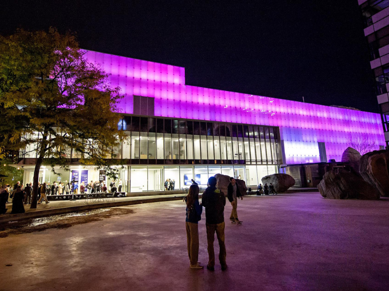 Two people look at the vivid purple LED panels affixed to Ryerson Image Center building