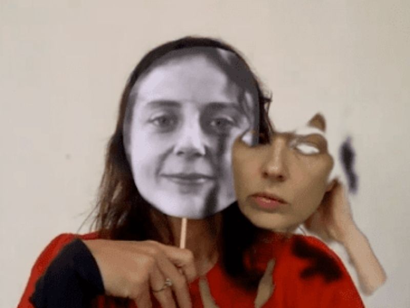 A film still of a woman with a distorted face via editing software. Her face is in black and white color while her shirt is a bright red hue.