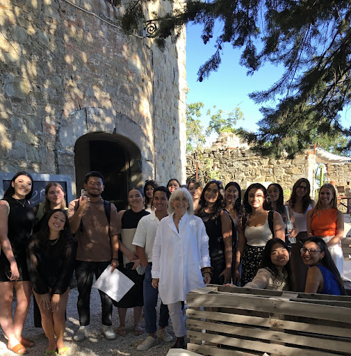 A group of students stand alongside their teacher smiling in front of a fortress