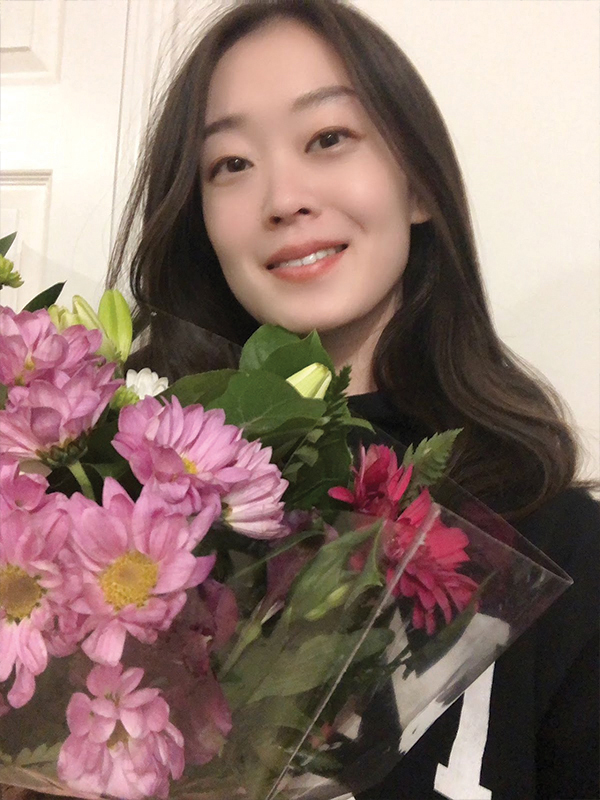 A headshot of a smiling woman holding a bouquet of flowers