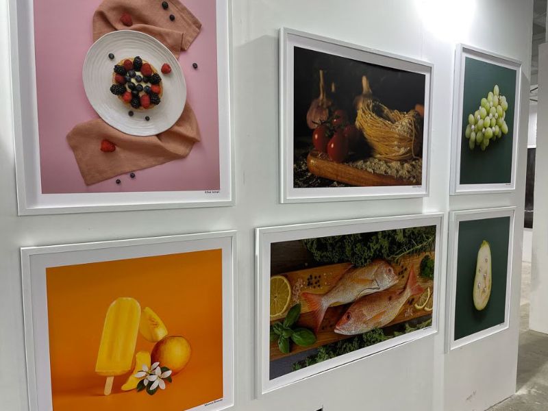 A wall with six framed images depicting various foods, including grapes, berries, fish and popsicles.