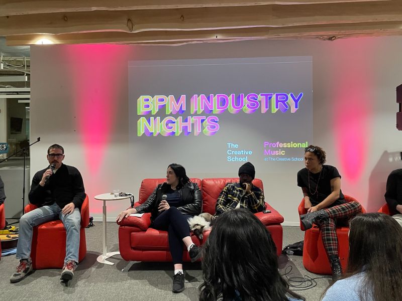 Four panellists sit before an audience of students in the Catalyst. “BPM Industry Nights” typed in colourful text is projected on the wall behind them