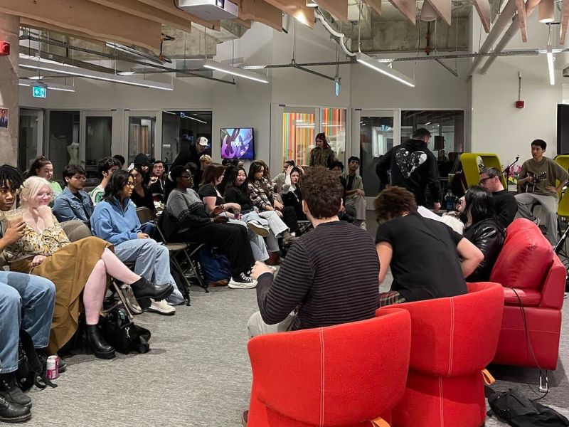 Students are seated in the audience of the Catalyst while industry leaders seated facing them have a discussion.