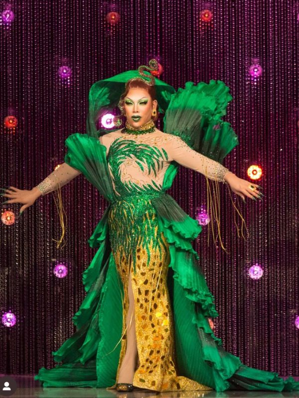 Drag queen Kiki Coe in an elaborate green and gold costume on stage