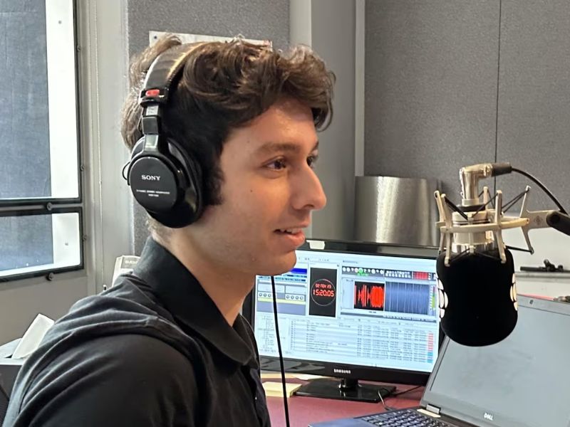 Side profile of Joseph Ryan wearing headphones and speaking into a microphone while sitting in a broadcast room