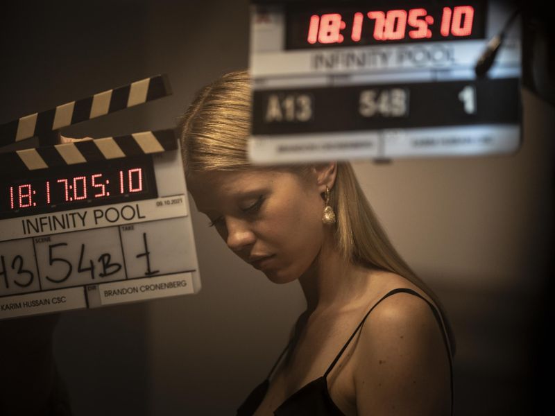 A woman with blonde hair looks down at the ground with two clapperboards in the foreground.