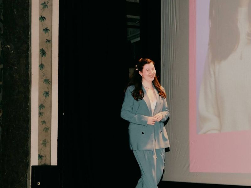 Woman smiling wearing a blue blazer and pants walking across a stage