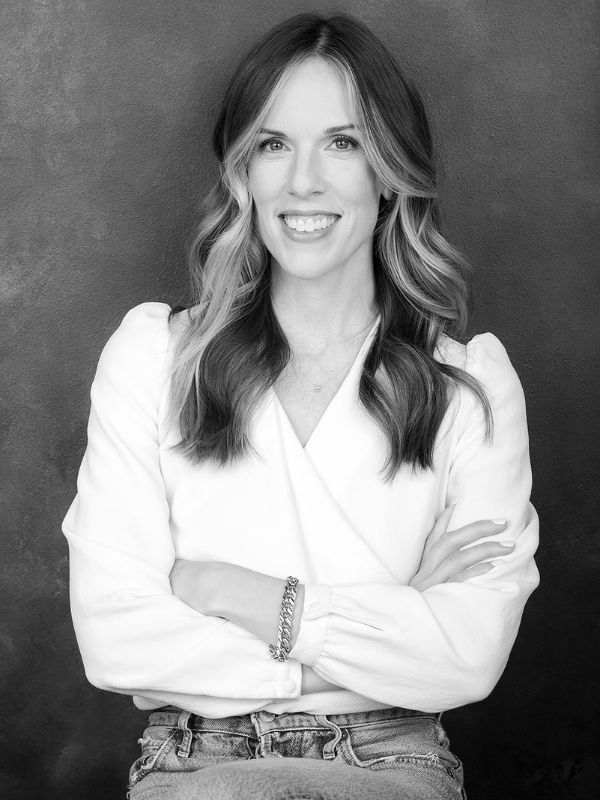 A woman in a white blouse smiling for a picture with her hands crossed