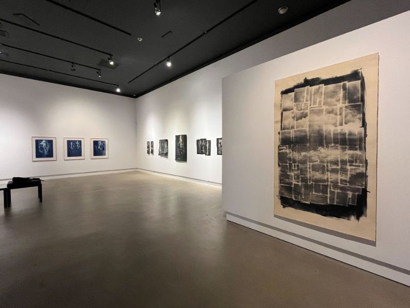 Inside an art gallery with black and white artwork on the wall under a spotlight