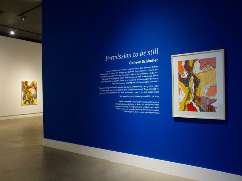 The entrance of a gallery exhibition featuring a work of art on a dark blue wall