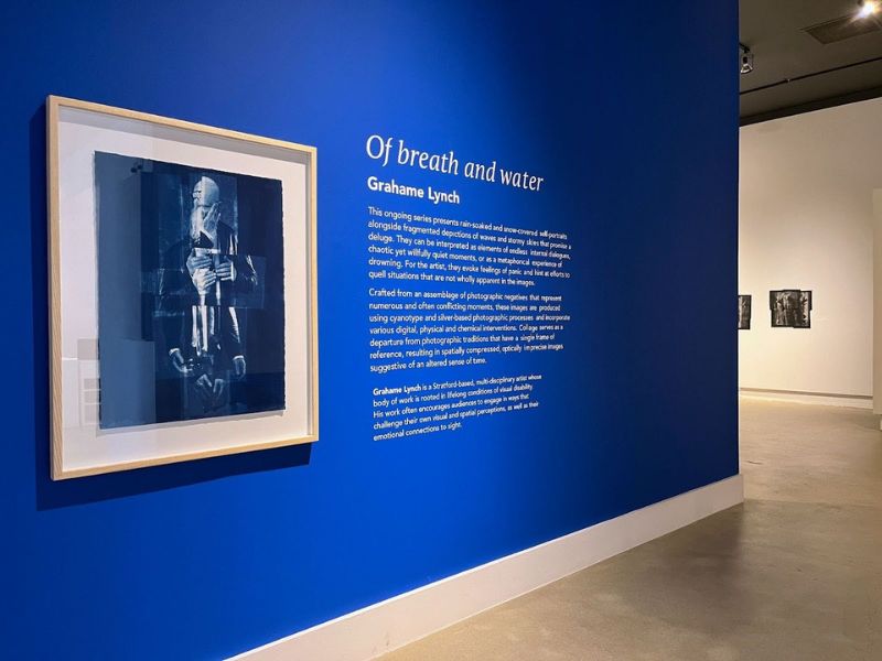 The entrance of a gallery exhibition featuring a work of art on a dark blue wall