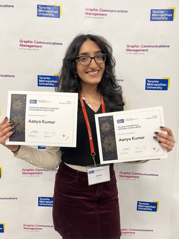 Aanya Kumar posing with the Canadian Printing Industries Scholarship Trust Fund (CPISTF) Award and William Somerville Memorial Award for Excellence certificates