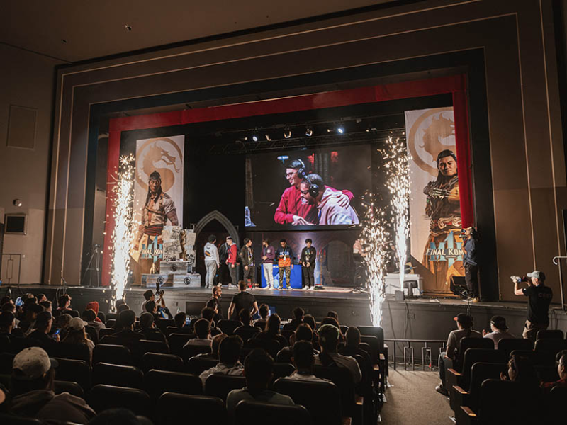 A wide shot of people standing on the stage and the audience celebrating the winners of the Mortal Kombat 1 2024 World Championship