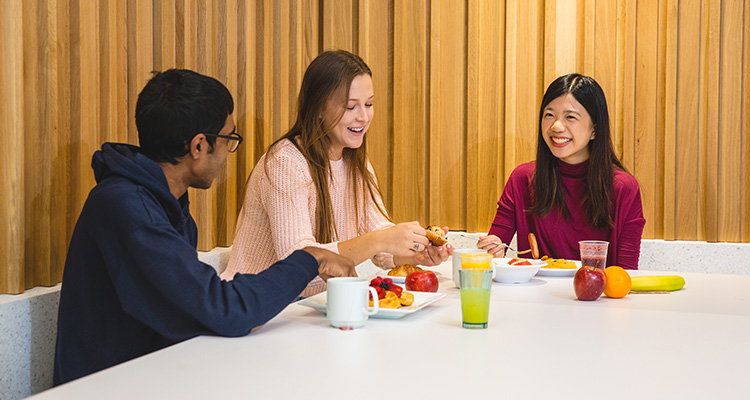 Three students in the Pitman Dining Hall chatting over a meal