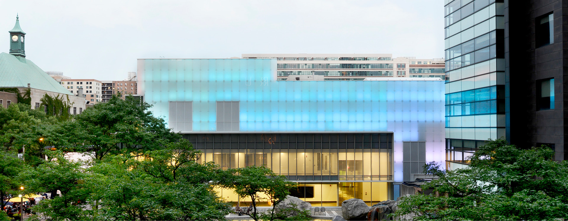 The RIC building lit up with blue lights, framed by the green trees of Lake Devo.