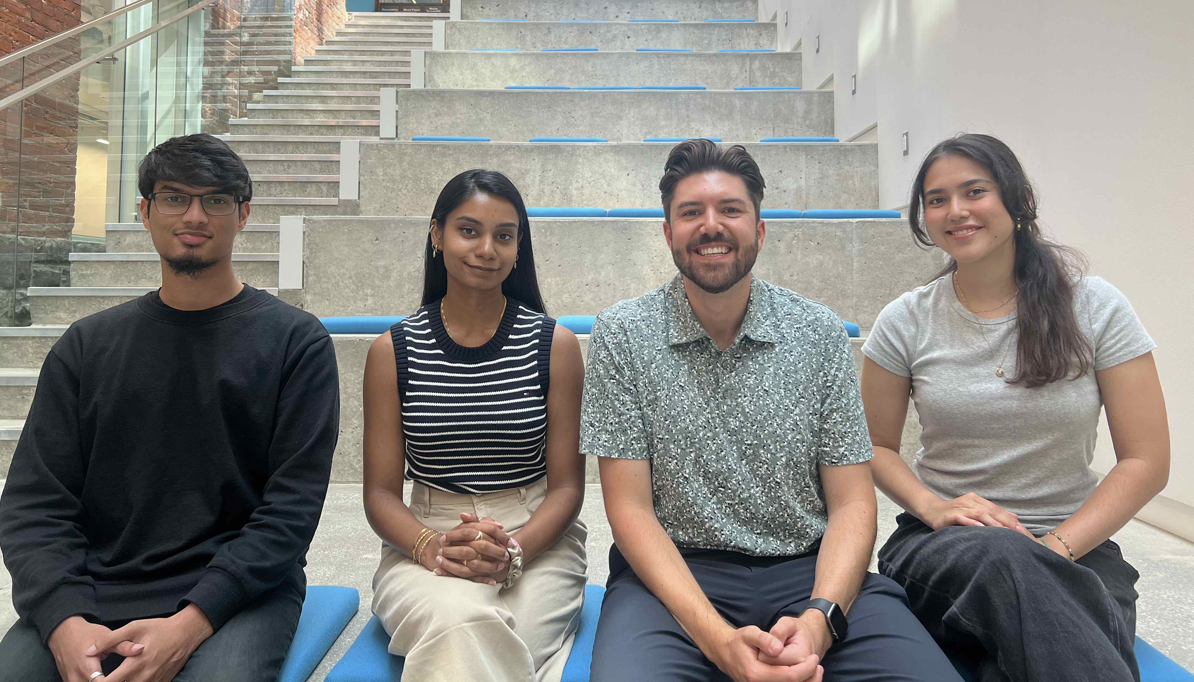 The four team members of the SDZ sitting in a row on steps in an atrium